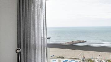 Un dormitorio con un ventanal grande que da a una playa y un estacionamiento.