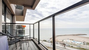A balcony with a view of the sea, a table with chairs, and a vase with flowers. - Bright apartment just steps from the ocean, with a pool and gym (Mar del Plata)