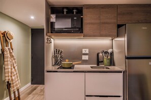 A compact kitchen with a microwave, stove, and refrigerator. - Premium Studio | Pool, Gym, and Coworking Space (Buenos Aires)