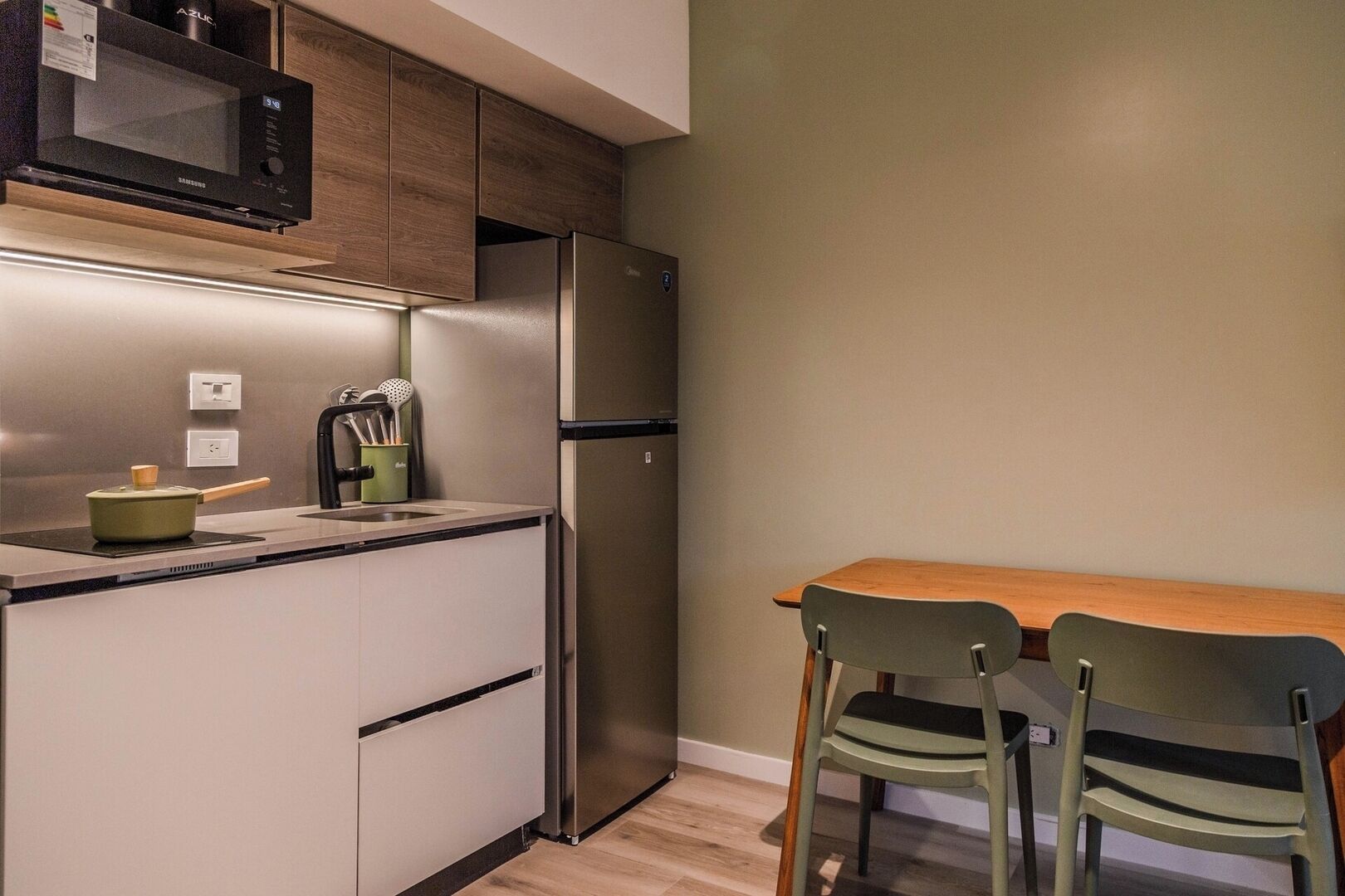 A compact kitchen with a microwave, refrigerator, and a small dining area with two chairs.