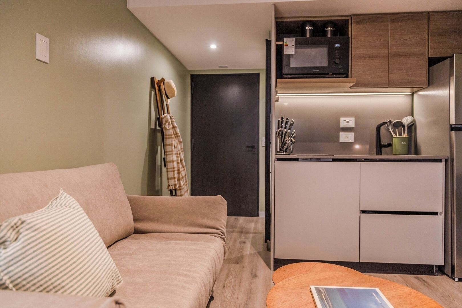 A compact living space with a kitchenette, a sofa, and a small table.