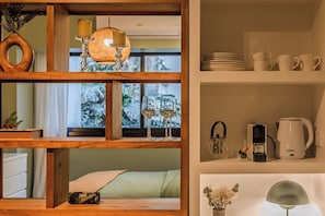 A room with a wooden shelf containing a vase, candles, and a lamp. There are also wine glasses on the shelf. - Premium Studio | Pool, Gym, and Coworking Space (Buenos Aires)