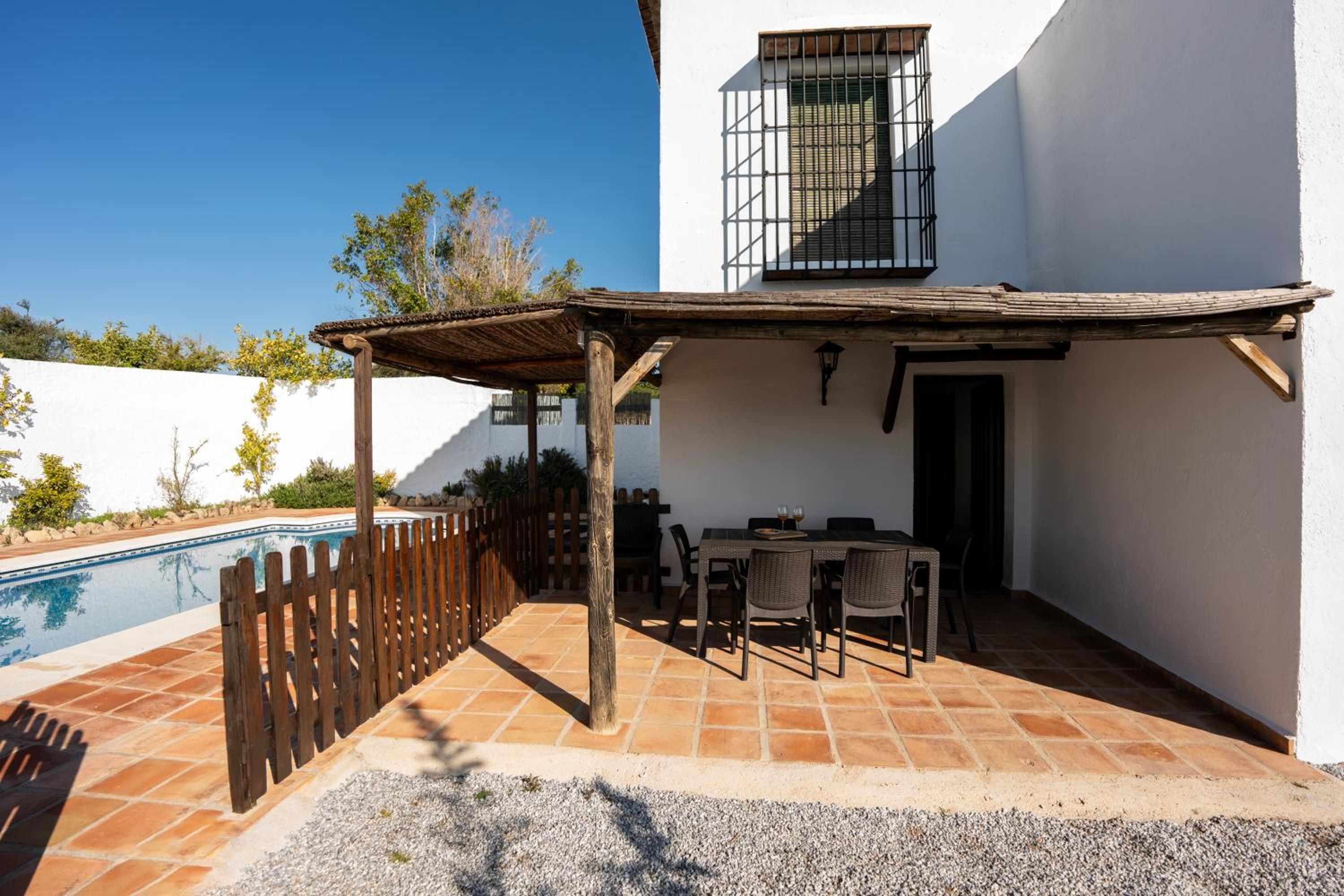Un patio con piscina, mobiliario exterior y una pérgola.
