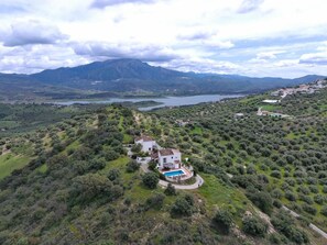 A villa with a swimming pool surrounded by olive groves and a mountainous backdrop. - Casas de Cantoblaco (Benamargosa)
