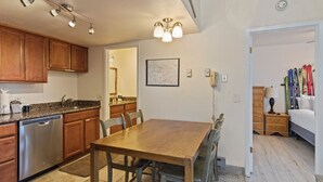 Una cocina con armarios de madera, lavavajillas y un comedor con mesa y sillas de madera.