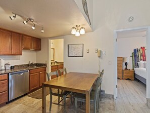 Une cuisine dotée de meubles en bois, d’un lave-vaisselle et d’un coin repas avec une table et des chaises en bois.