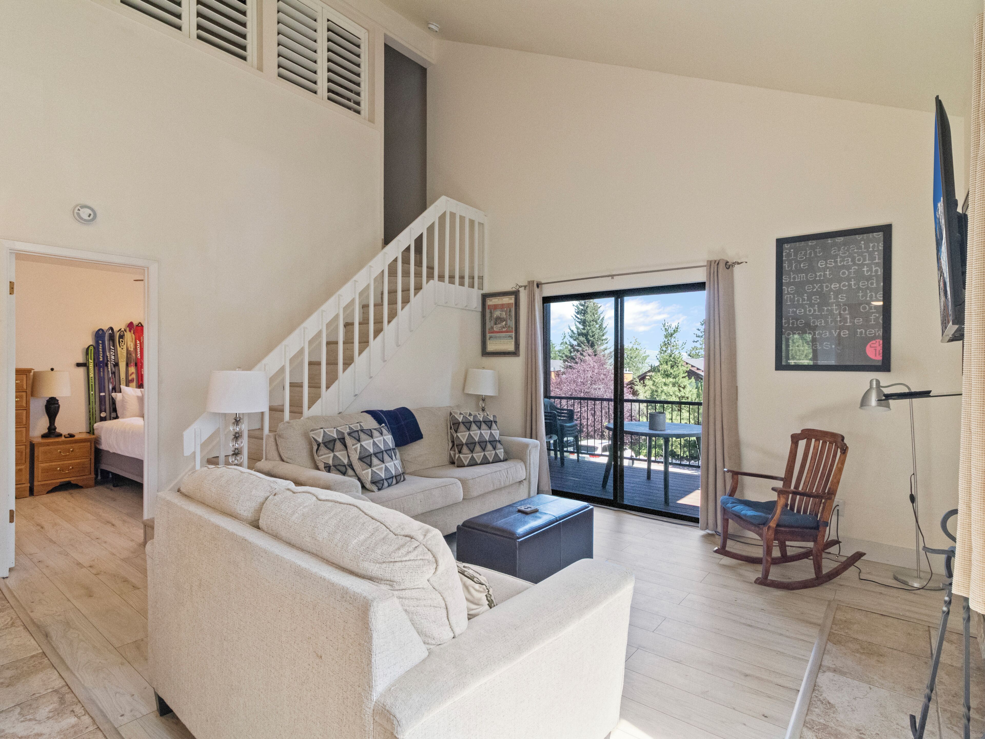 Un salon avec un escalier, un canapé, une table basse et une vue sur l’extérieur.