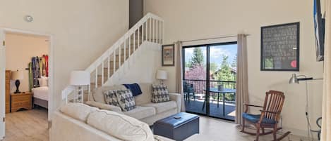 Un salon avec un escalier, un canapé, une table basse et une vue sur l’extérieur.