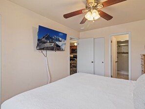 A bedroom with a bed, a ceiling fan, a mounted TV, and a door leading to a bathroom. - Red Pine A8 | Pools | Hot Tubs | Balcony | BBQ | Sleeps 8 (Park City)