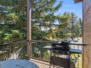 Ein Balkon mit Grill, mit Blick auf eine Straße mit parkenden Autos und Bäumen.