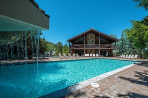 Une piscine avec des chaises longues et un bâtiment doté d’un balcon.