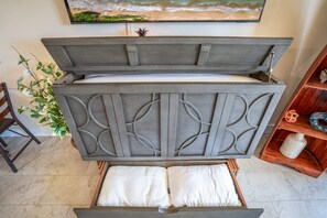 Ein Zimmer mit einem Bett, einem an der Wand befestigten Fernseher und einer Pflanze.