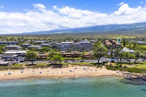 Ein Küstenresort mit mehreren Hotelgebäuden, einem Sandstrand und klarem, türkisblauem Wasser.