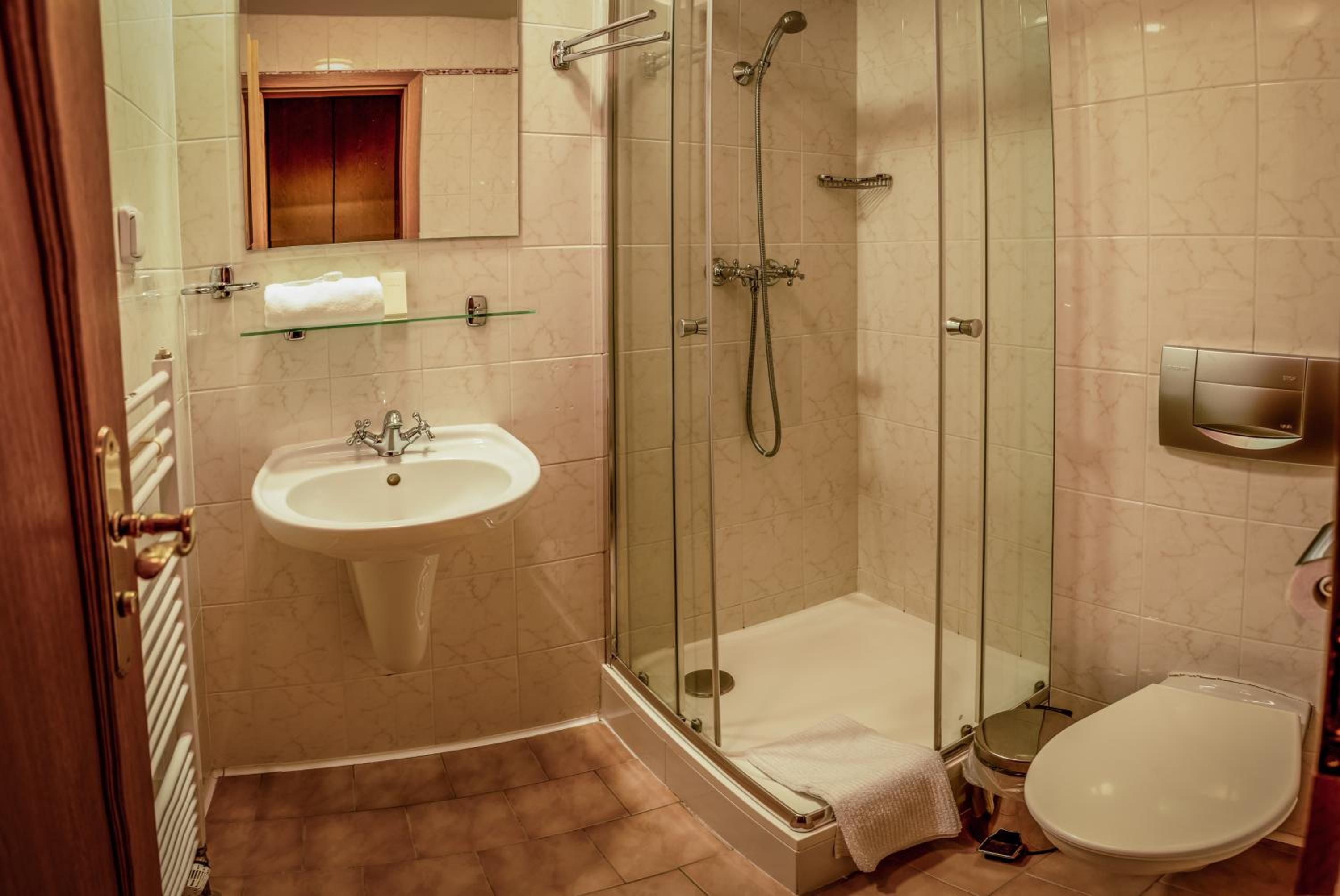 A bathroom with a glass-enclosed shower, a sink, and a toilet.