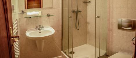 A bathroom with a glass-enclosed shower, a sink, and a toilet.