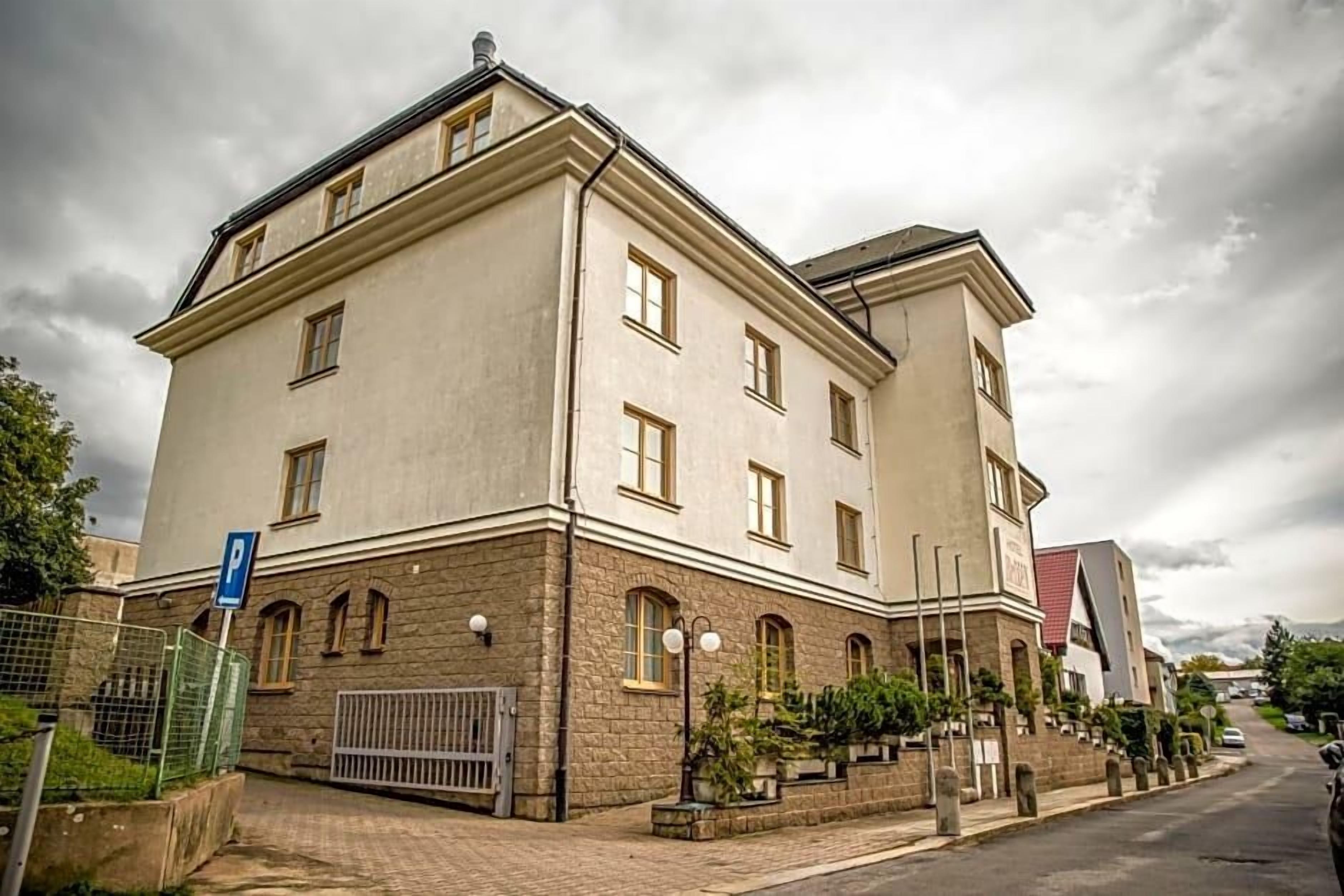 A multi-story building with a stone facade, multiple windows, and a parking sign.