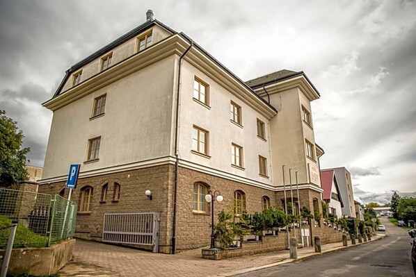 A multi-story building with a stone facade, multiple windows, and a parking sign.