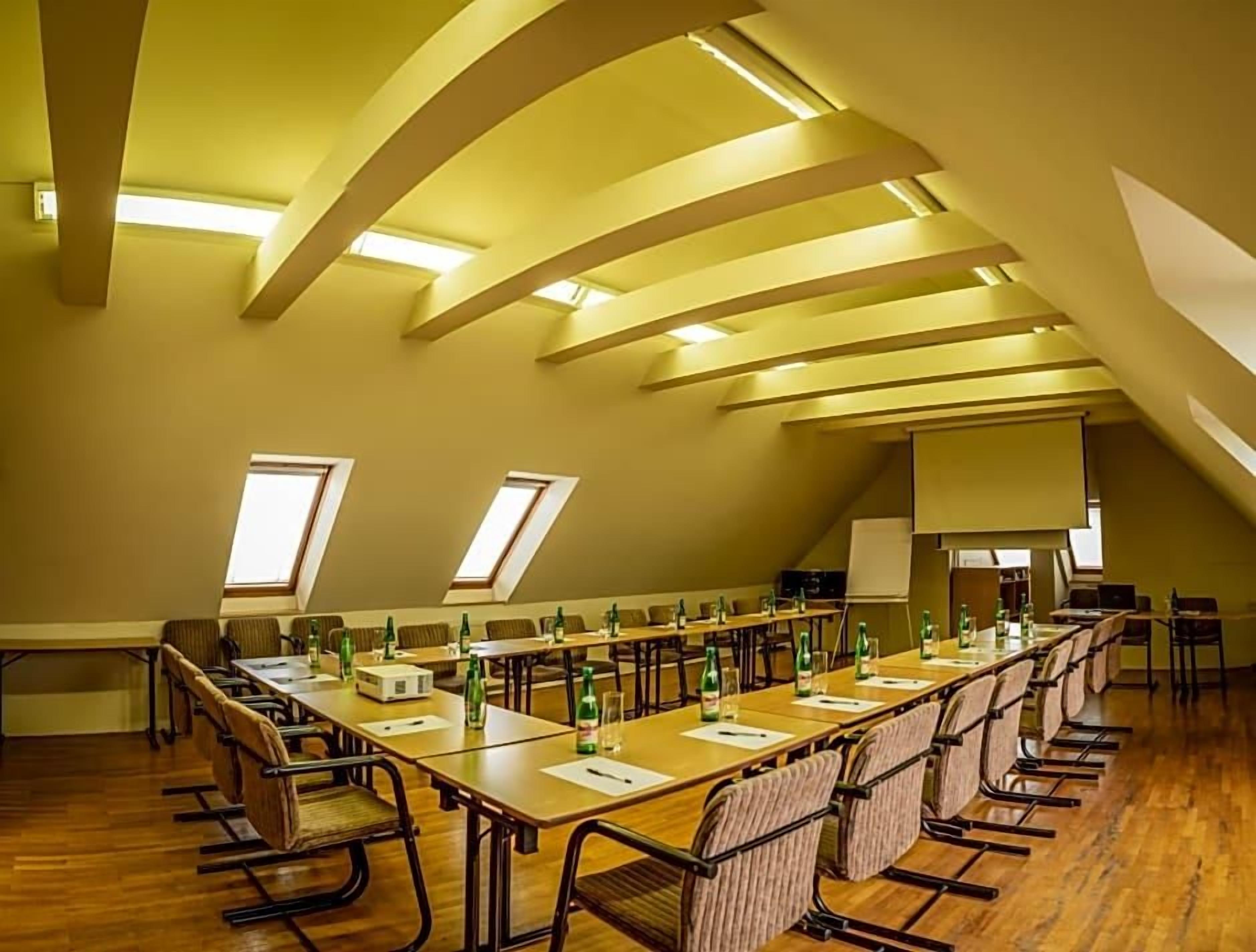 Un salón de conferencias con una mesa larga, sillas y una pizarra.