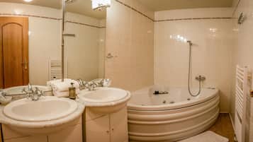 A bathroom with two sinks, a bathtub, and a shower.