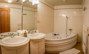 A bathroom with two sinks, a bathtub, and a shower.