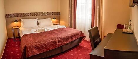 Una habitación de hotel con una cama, lámparas de noche, un escritorio y una silla.