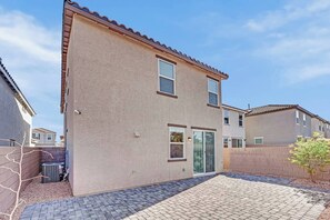 A two-story residential building with a brick facade, a front door, and a small garden area with a paved walkway. - Modern 4B3B|FiberWiFi|King Bed|NearStrip (Las Vegas)