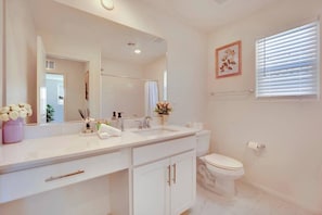 A bathroom with a white vanity, a large mirror, a toilet, and a window with blinds. - Modern 4B3B|FiberWiFi|King Bed|NearStrip (Las Vegas)