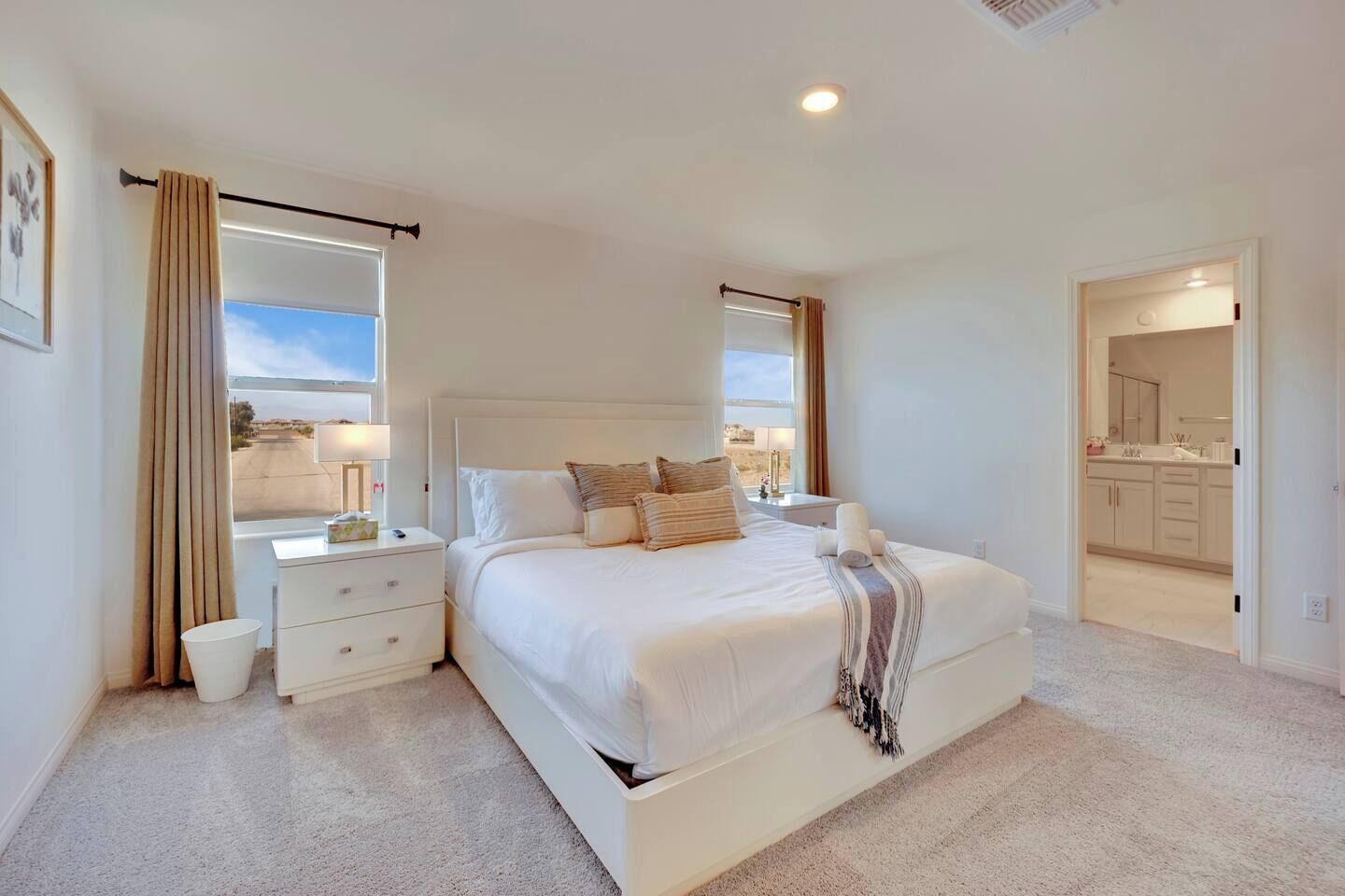 Un dormitorio con una cama grande, mesitas de noche, un ventanal con cortinas y vistas al exterior.