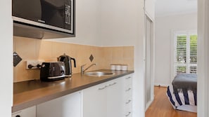 A modern kitchen with a microwave, toaster, kettle, and sink. - Collins by the Sea - Beachfront (Casuarina)