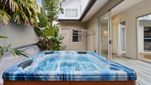 A hot tub in a modern outdoor setting with a sliding glass door leading to a living area. - Collins by the Sea - Beachfront (Casuarina)