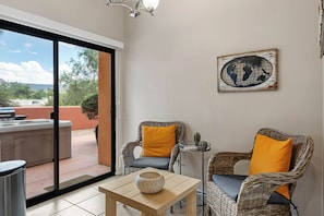 A room with wicker chairs, a small table, a globe artwork, and a sliding glass door leading to an outdoor area with a barbecue. - 2BR Sedona retreat with red rock views, hot tub, Wi-Fi, and patio. (Sedona)