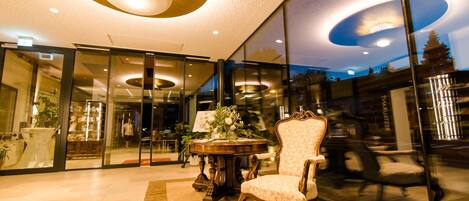 A modern interior with a round table, a chair, and a glass wall reflecting the outside.
