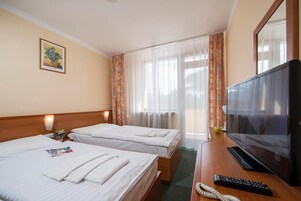 Habitación de hotel con dos camas, un televisor y un escritorio con control remoto.