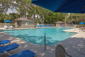 A swimming pool with lounge chairs and umbrellas, surrounded by trees and a building. - Egret Point HH-3 Bed/3 bath Condo- play golf & enjoy Hilton Head!  Full kitchen (Hilton Head Island)