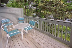 A wooden deck with a table and four chairs, surrounded by a white railing. - Egret Point HH-3 Bed/3 bath Condo- FREE golf for foursome daily; Full kitchen (Hilton Head Island)