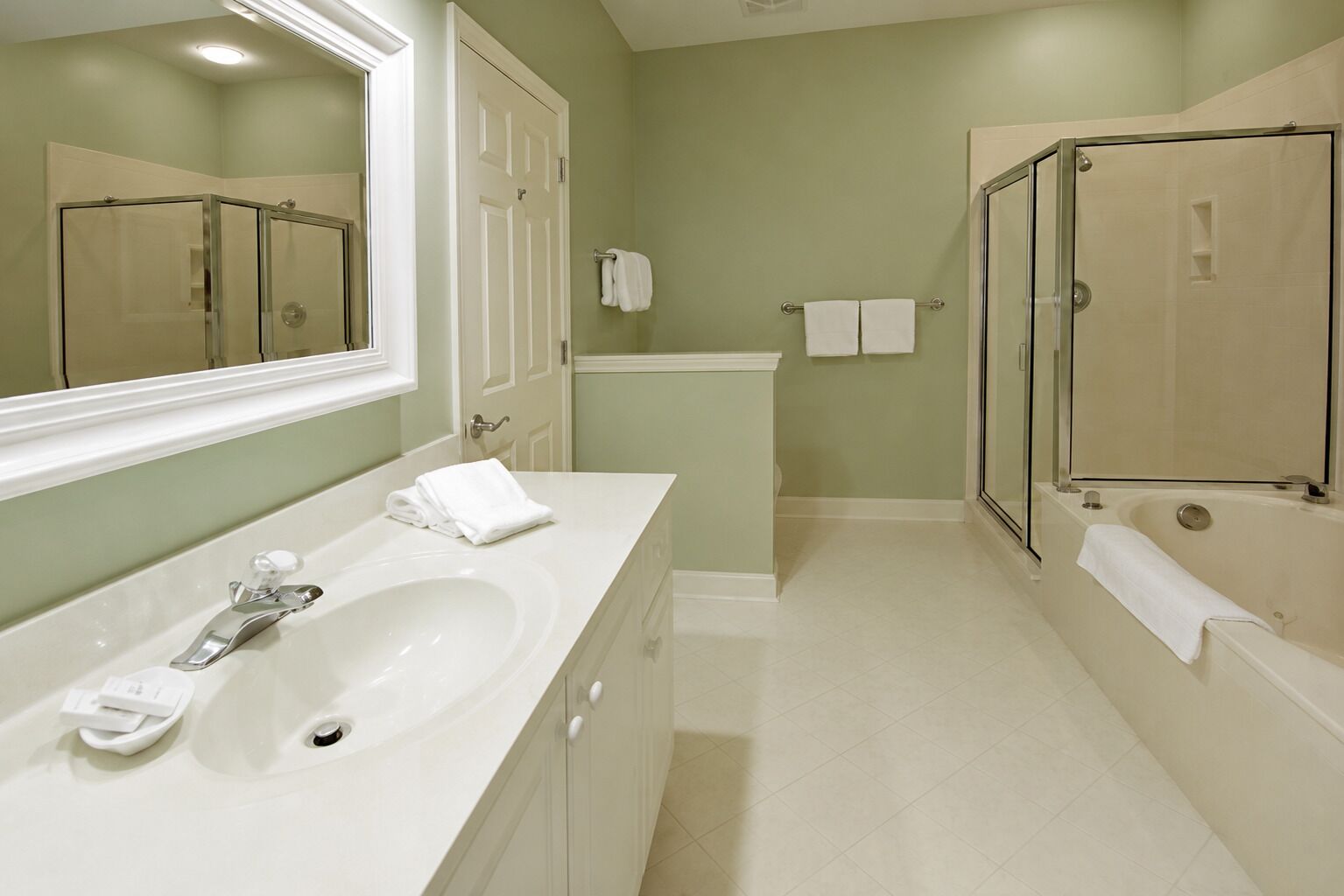 A bathroom with a large mirror, a sink, a bathtub, and a shower area.