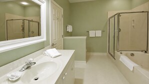 Une salle de bain avec un grand miroir, un lavabo, une baignoire et un espace douche.