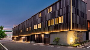 Un edificio moderno con fachada plana, amplios ventanales y una entrada bien iluminada.