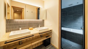 Un baño moderno con dos lavamanos, un espejo grande y una zona de ducha.