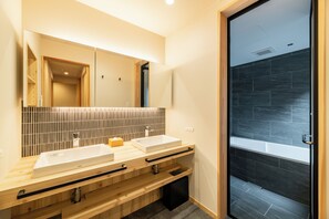Ein modernes Badezimmer mit zwei Waschbecken, einem großen Spiegel und einer Duschkabine.