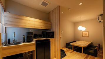 A compact kitchen with modern appliances, a dining area with a wooden table, and a pendant light.