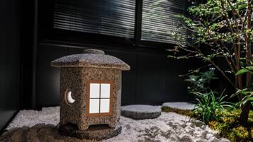 Un farol de piedra con una ventana, sobre una superficie rugosa con musgo y plantas.