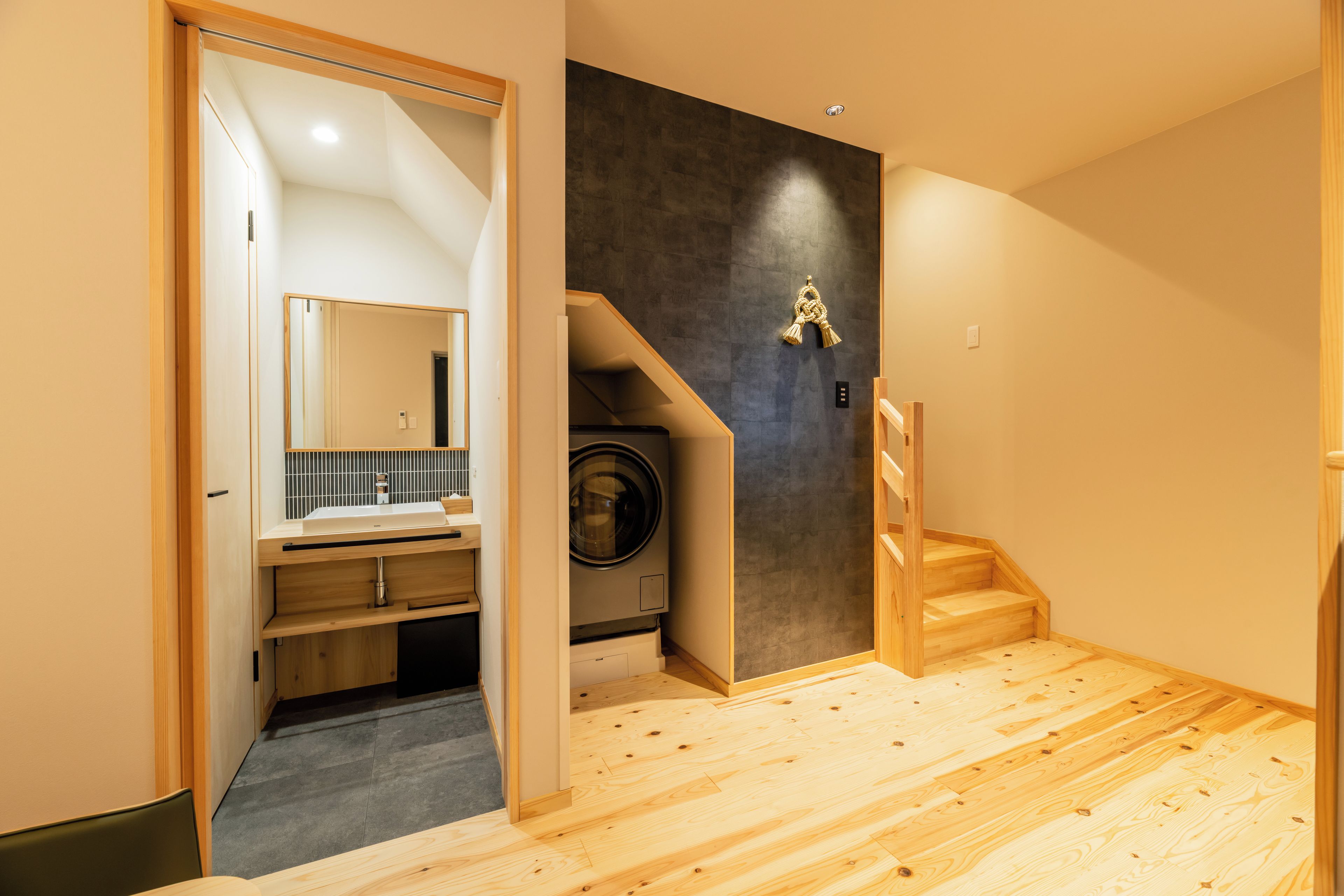 A modern bathroom with a wooden floor, a sink, and a mirror.