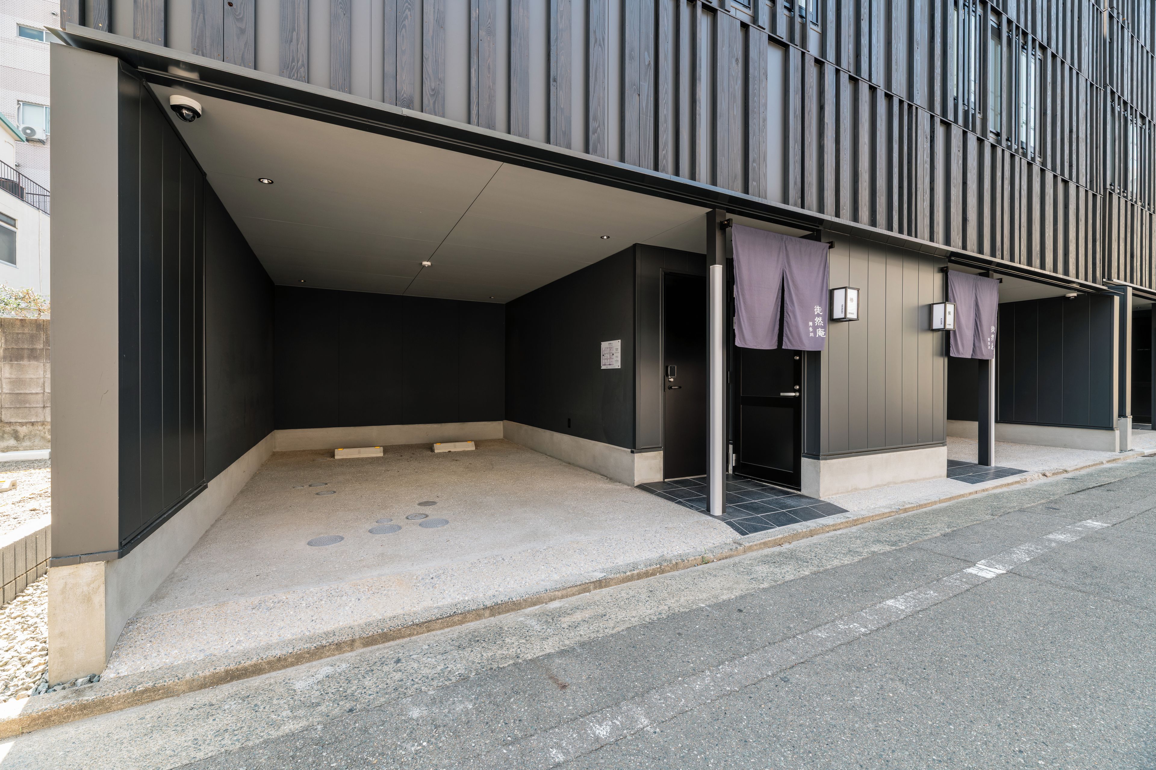 A modern building with a covered entrance and a parking area.