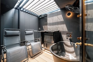 Ein modernes Badezimmer mit Dachfenster, einer Badewanne und zwei Sitzbereichen.