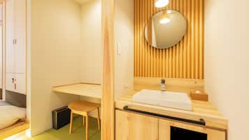 A modern bathroom with a wooden vanity, a round mirror, and a small stool.