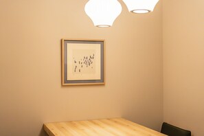 A room with a wooden table and a framed artwork on the wall. - Tsurezure-Ann Hakatagawa (Shimogofukumachi Hakata-ku, Fukuoka-shi)