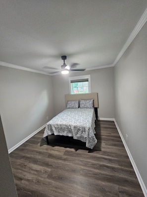 A bedroom with a bed, a ceiling fan, and a window with blinds.