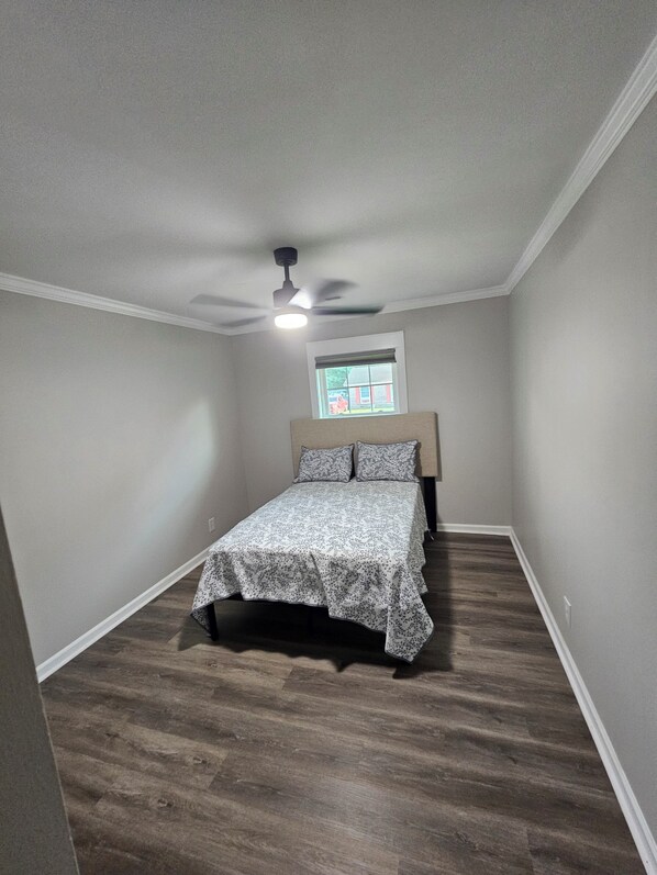 A bedroom with a bed, a ceiling fan, and a window with blinds.
