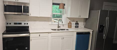 Una cocina moderna con armarios blancos, electrodomésticos de acero inoxidable y un lavavajillas azul.